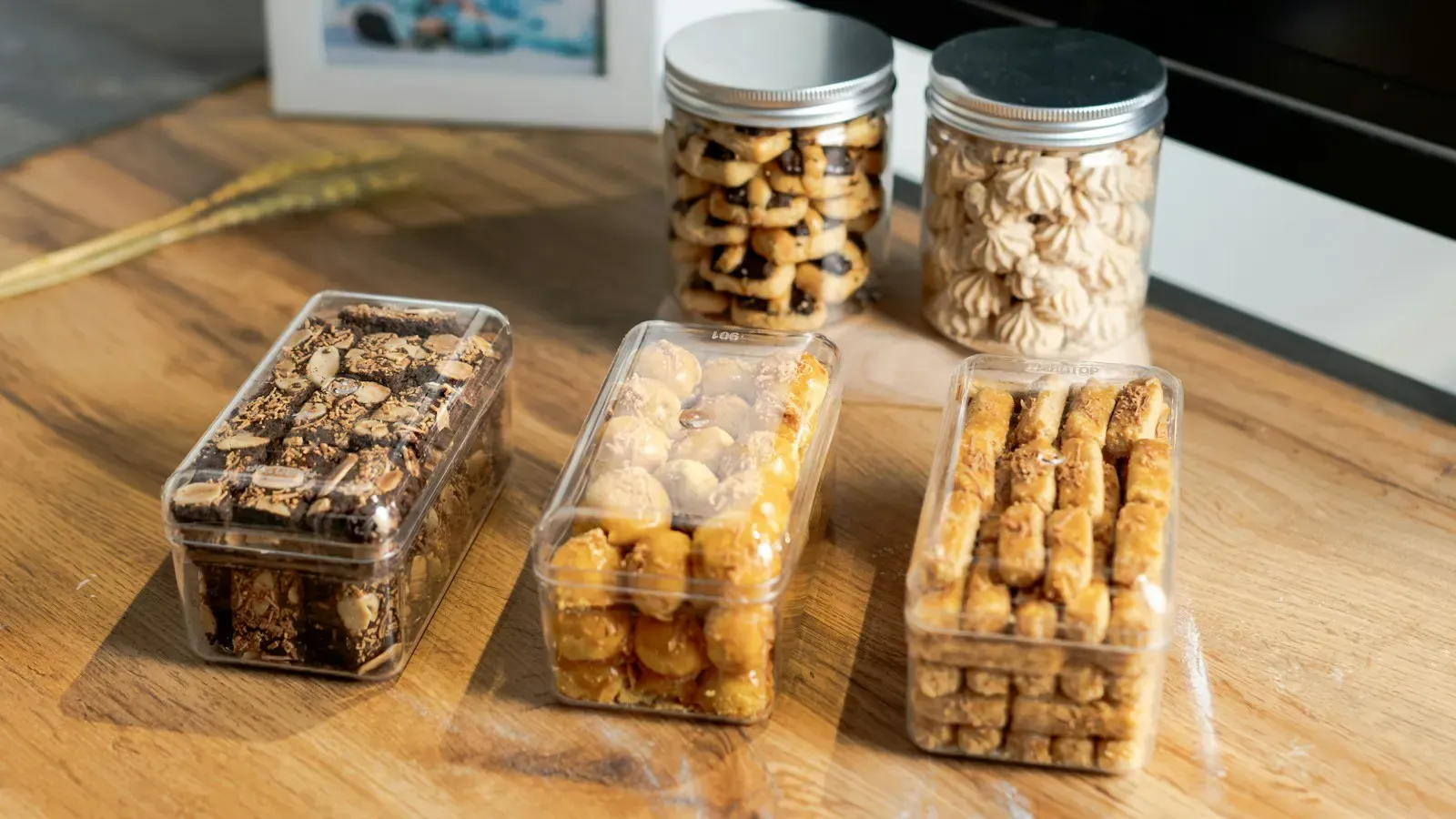 Doces e biscoitos embalados em potes transparentes sobre a mesa, prontos para entregar