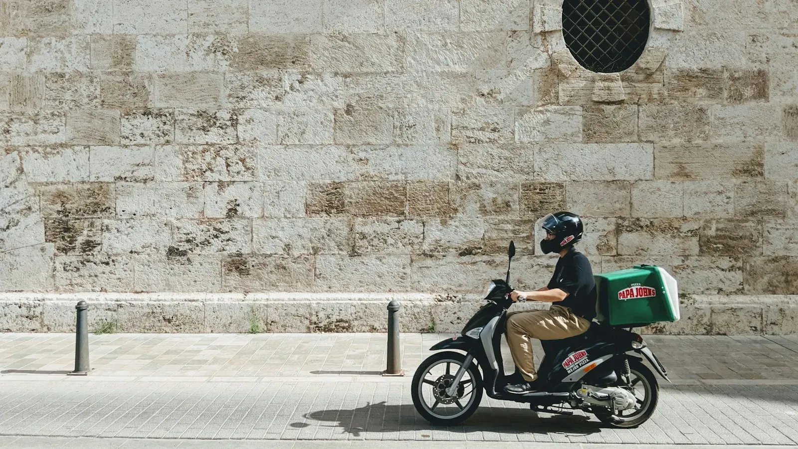 Entregador numa moto com a caixa de entrega nas costas
