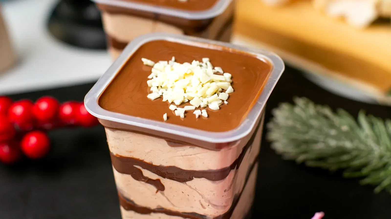 Bolo de pote em copo transparente, com camadas de creme e recheio de chocolate e raspas de chocolate branco por cima