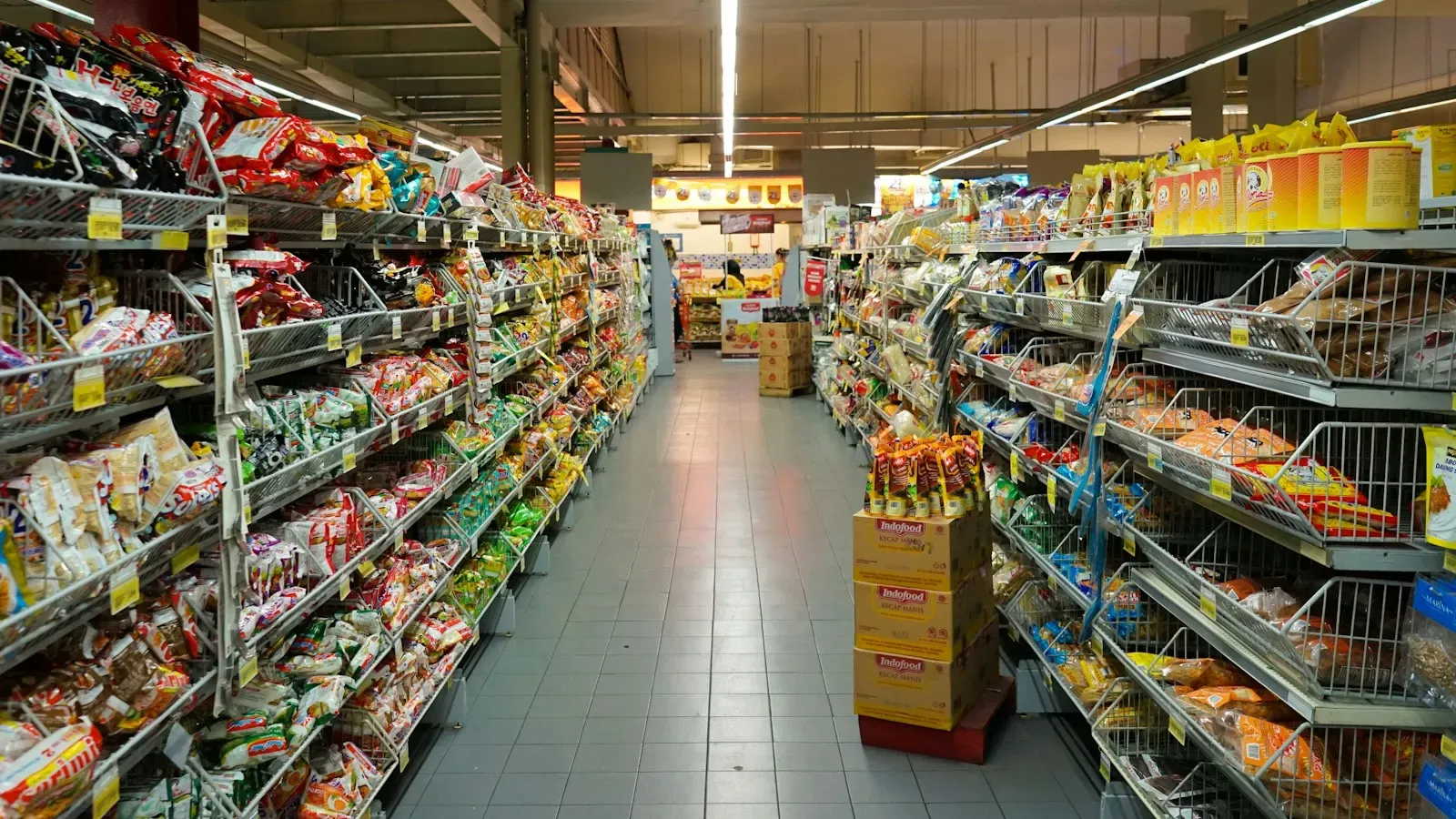 A grocery store aisle seen down its length, shelves stocked on both sides